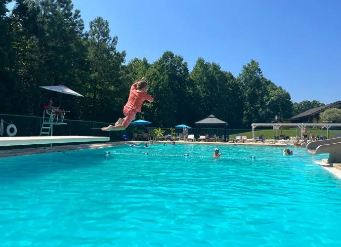 Swimmer leaping off the diving board into the outdoor pool at Asheboro Racquet & Swim Club on a sunny day