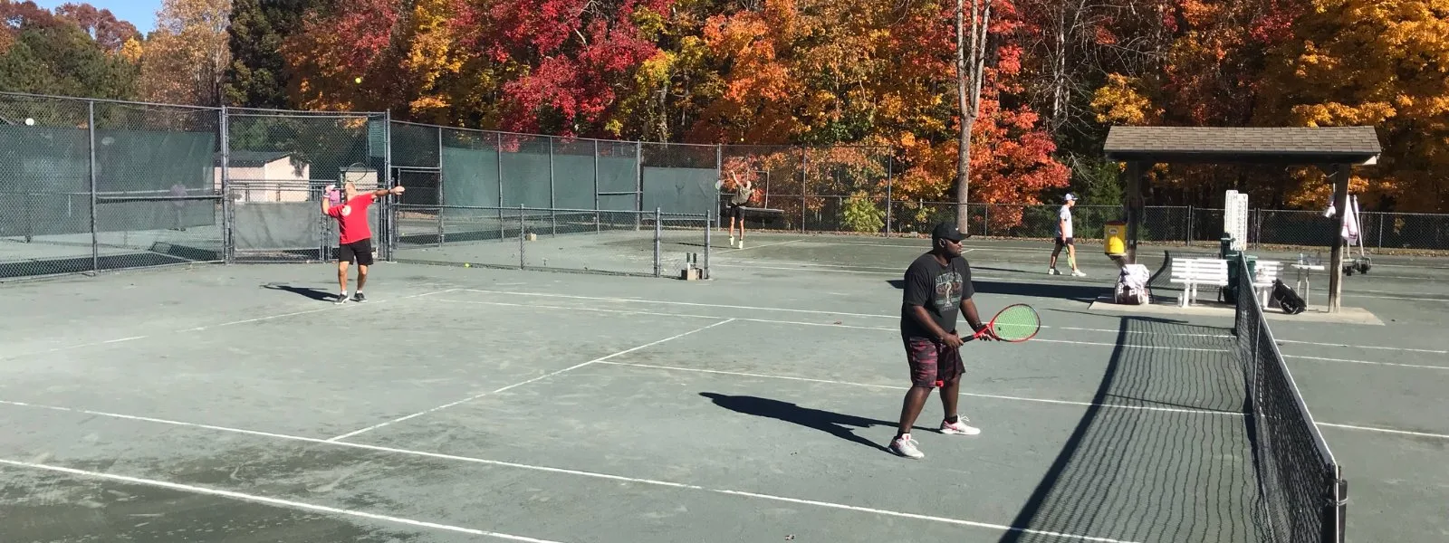 Adults playing tennis on the courts amid bright fall foliage at Asheboro Racquet & Swim Club
